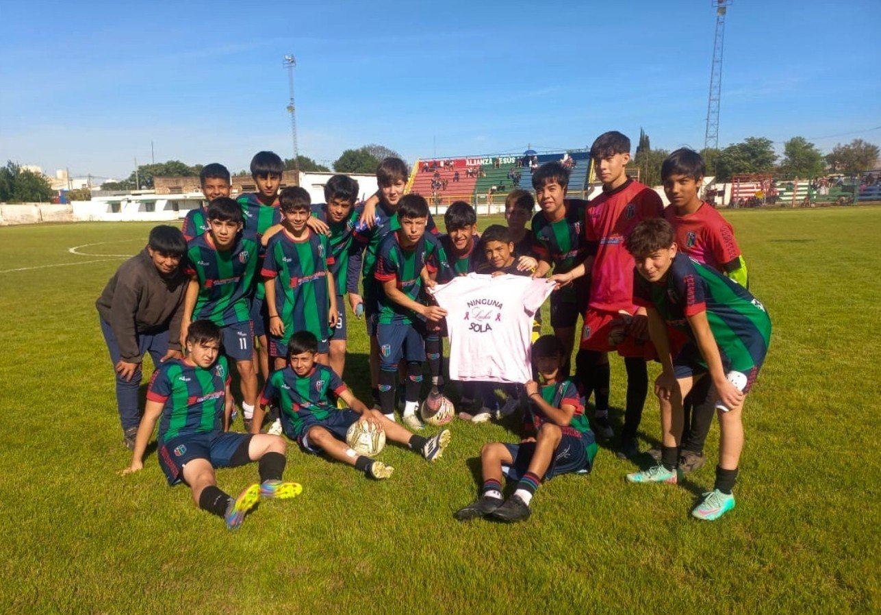 Jugadores de fútbol de Alianza Jesús María posan en la cancha mostrando una remera rosa con el lema “Ninguna lucha sola”, en el marco de la campaña de concientización sobre el cáncer de mama.